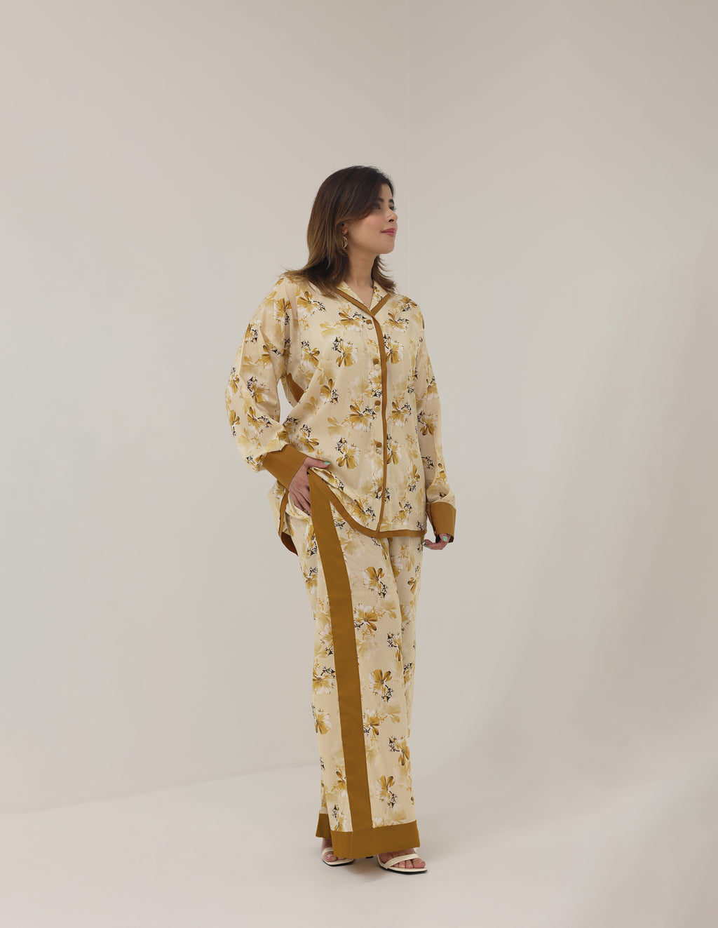 Woman wearing a floral pajama set with brown accents on a white background